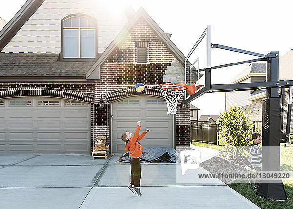 Junge spielt Basketball mit Bruder im Hinterhof
