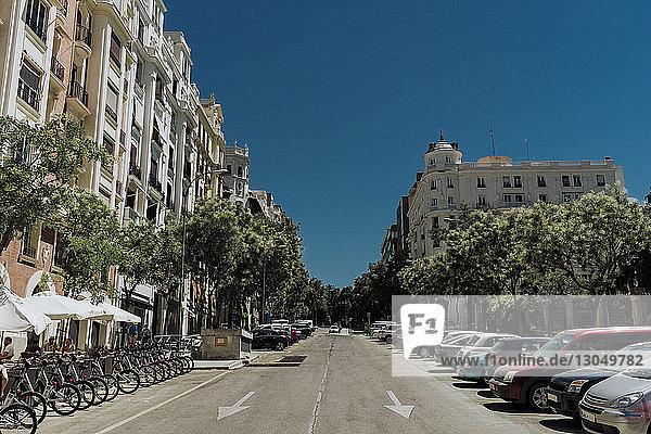 Autos und Fahrräder parken auf der Straße inmitten von Gebäuden bei strahlend blauem Himmel am sonnigen Tag