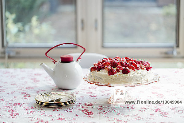 Vanillekuchen mit Wasserkocher und Tellern auf dem Tisch