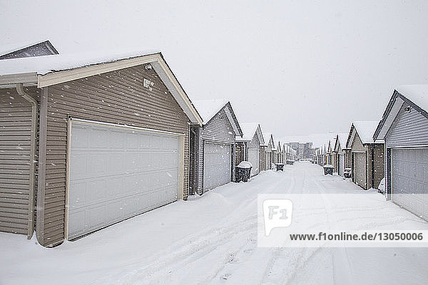Häuser in Reihe gegen klaren Himmel bei Schneefall