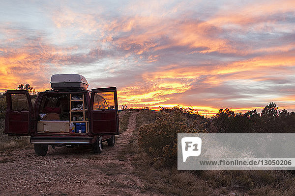 Lieferwagen bei Sonnenuntergang vor bewölktem Himmel auf dem Feld geparkt