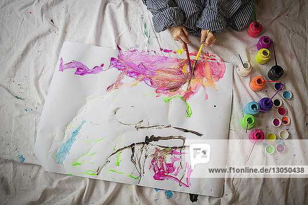 High angle view of boy painting on paper while sitting at home