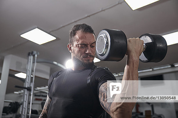 Selbstbewusster muskulöser Mann hebt Hantel im Fitnessstudio