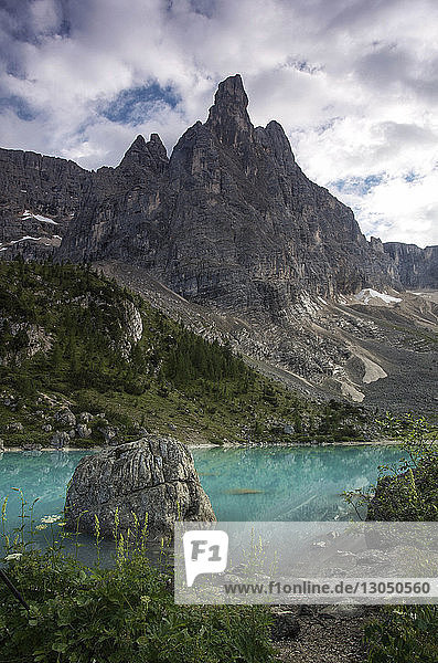 Tranquil scene of lake by mountain against cloudy sky