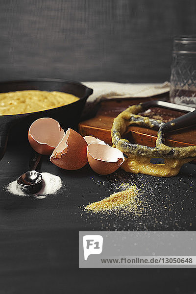 Nahaufnahme einer unordentlichen Küchentheke mit zerbrochenen Eierschalen und Küchenutensilien