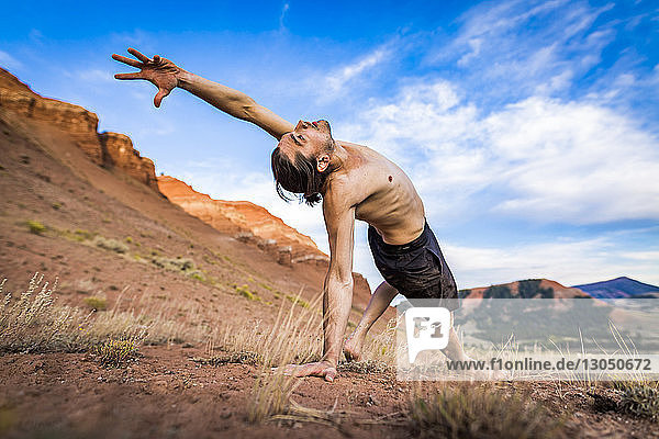 Shirtless man practicing yoga while exercising against sky at Bridger-Teton National Forest