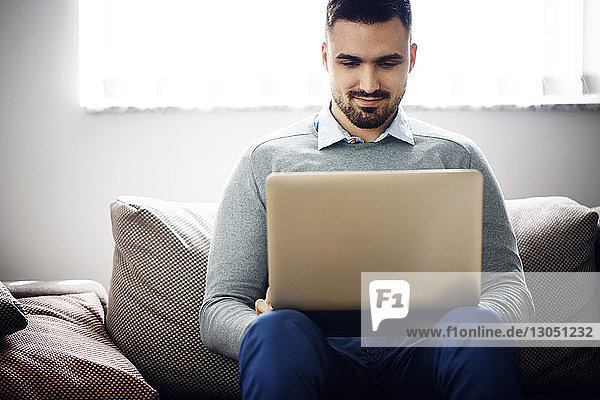 Businessman using laptop on couch in office lobby