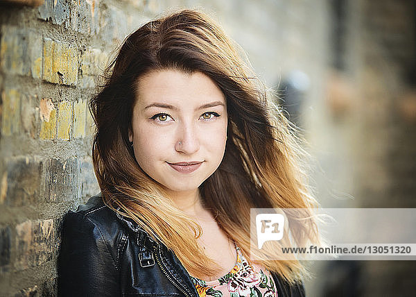 Close-up portrait of confident teenage girl against wall