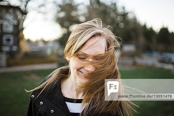 Fröhliches Teenager-Mädchen wirft Haare im Park