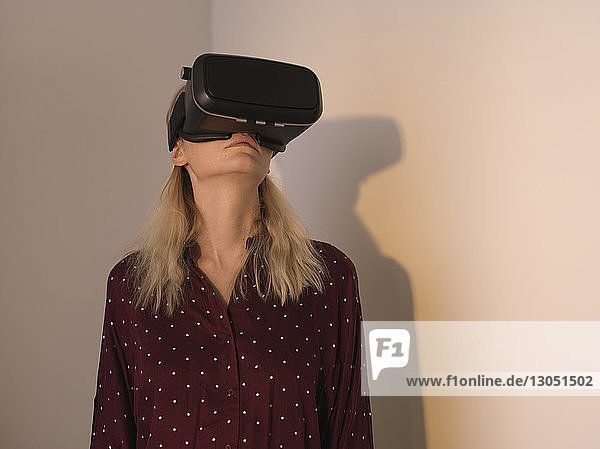 Frau benutzt Virtual-Reality-Simulator  während sie zu Hause an Wänden steht