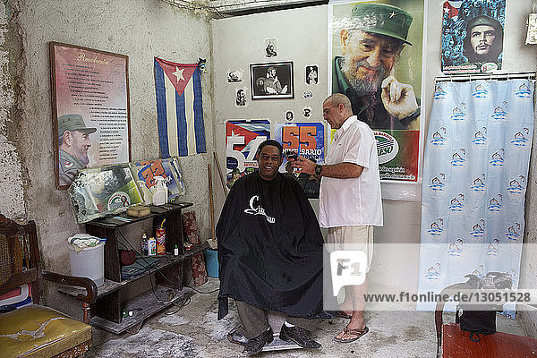 Side view of barber cutting man hair at salon