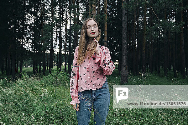 Porträt einer selbstbewussten jungen Frau im Wald stehend