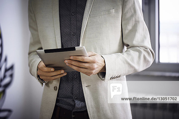 Midsection of businessman using tablet computer in creative office