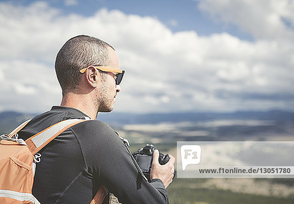 Hiker holding camera while looking at landscape
