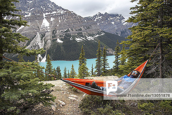 Hochwinkelaufnahme eines Wanderers  der sich in einer Hängematte am Peyto Lake und in den Bergen des Banff National Park ausruht