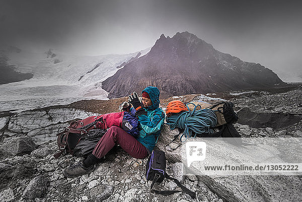 Rock climber by climbing equipment shielding from extreme weather  El Chaltén  south Patagonia  Argentina
