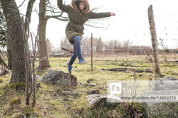 Mädchen springt im Feld von Fels zu Fels