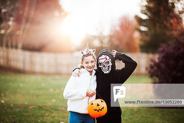 Geschwister in Halloween-Kostüm posieren im Park