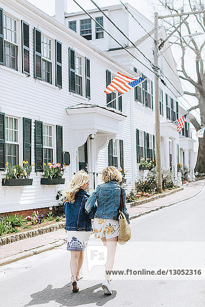 Zwei junge Freundinnen schlendern entlang der Dorfstrasse, Rückansicht, Menemsha, Martha's Vineyard, Massachusetts, USA