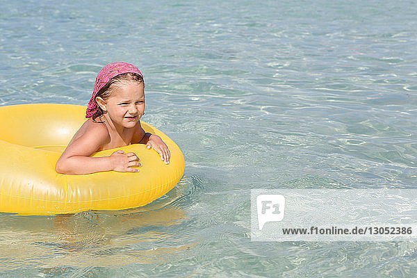 Mädchen spielt mit gelbem Schlauchboot im Meer  San Vito  Sizilien  Italien