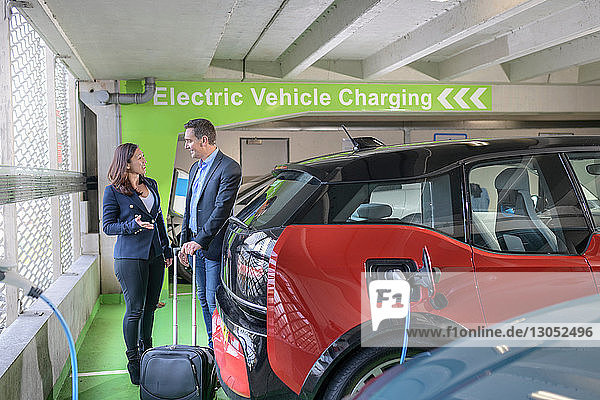 Man and woman charging electric car at charge bay Manchester UK