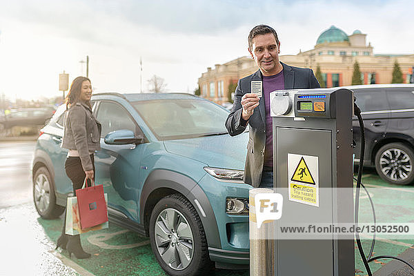 Man and woman charging electric car at car charging park Manchester UK
