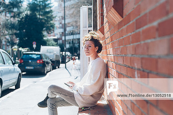 Frau mit Handy auf Bank in sonniger Strasse  Mailand  Italien