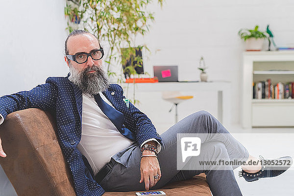 Cool hipster businessman sitting on office sofa  portrait
