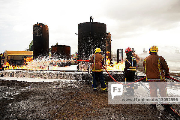 Firemen training  spraying firefighting foam onto oil storage tank fire at training facility
