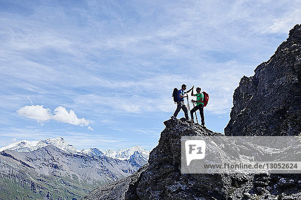 Hikers high fiving on peak of rock  Mont Cervin  Matterhorn  Valais  Switzerland