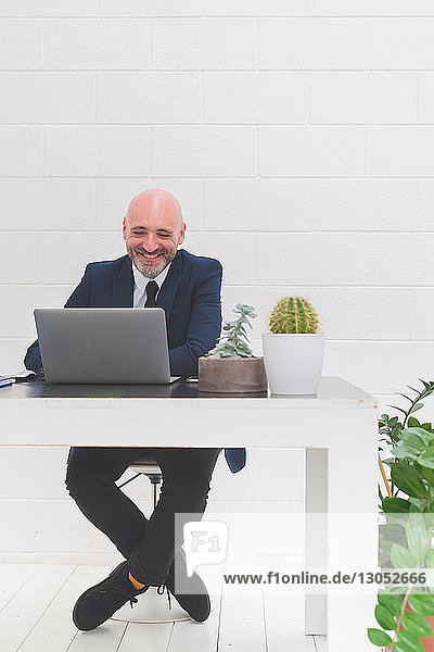 Businessman laughing while looking at laptop on office desk