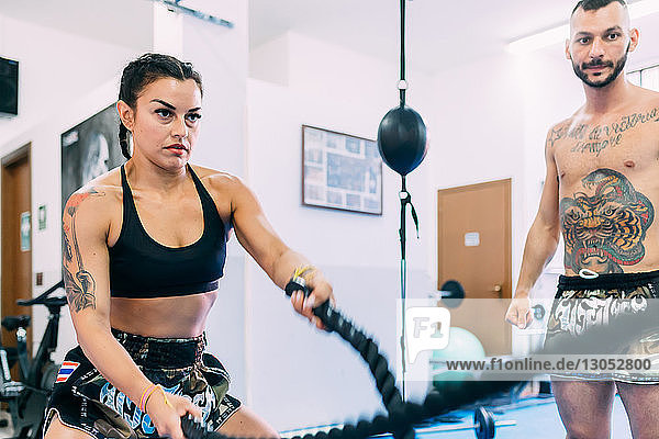 Woman using rope whips during workout in gym