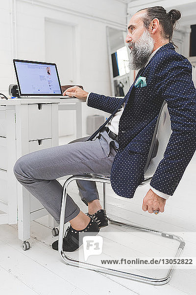 Stilvoller Geschäftsmann betrachtet Laptop auf Bürotisch