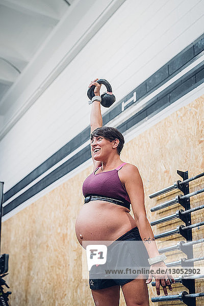 Schwangere Frau benutzt Kettlebell im Fitnessstudio
