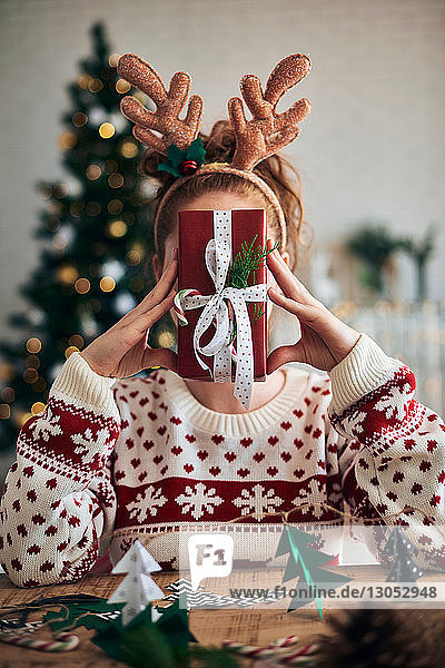 Frau hinter dem Weihnachtsgeschenk  Christbaumschmuck im Vordergrund