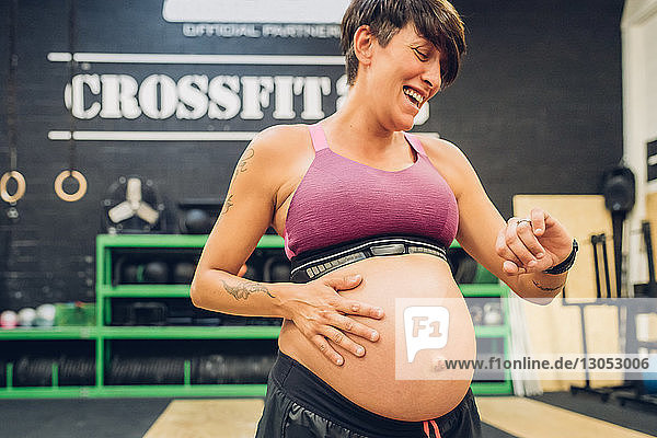 Schwangere Frau schaut auf die Zeit im Fitnessstudio