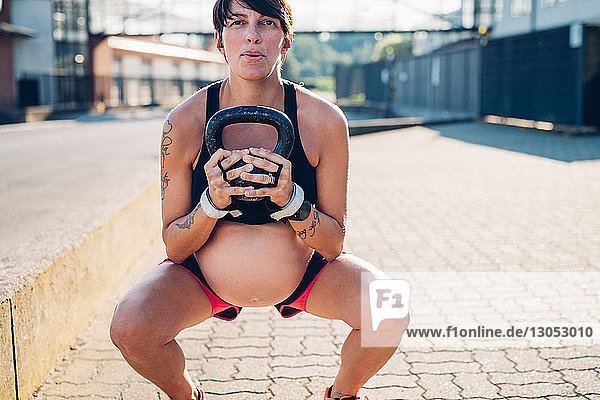 Schwangere Frau benutzt Kettlebell im Freien