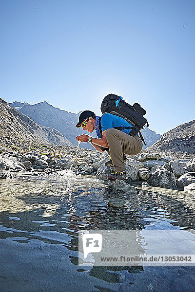 Hiker drinking from pool  Mont Cervin  Matterhorn  Valais  Switzerland