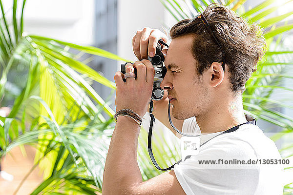 Fotografierender Mann  Palmenpflanze im Hintergrund