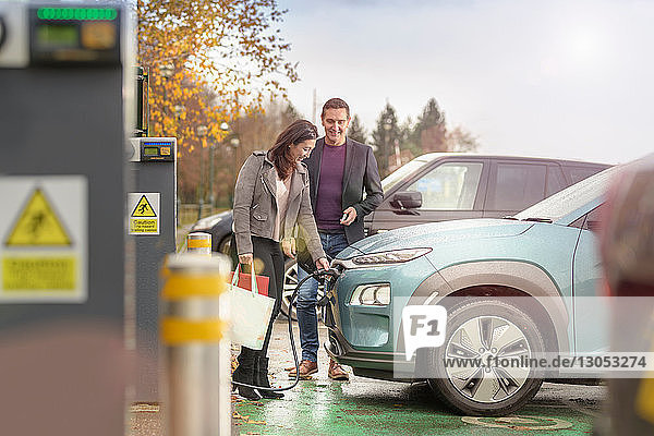 Man and woman charging electric car at car charging park Manchester UK
