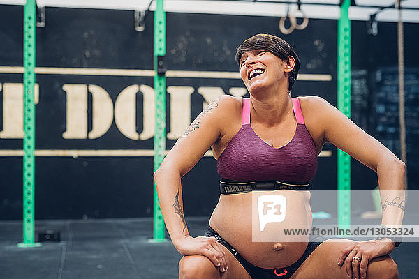Schwangere Frau lacht im Fitnessstudio