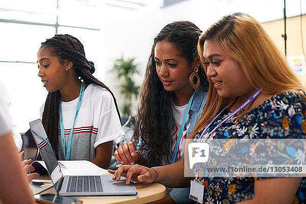 Weibliche und männliche Hochschulstudenten arbeiten im Team und benutzen den Laptop im Klassenzimmer der Hochschule