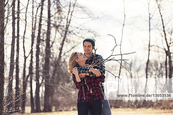 Happy man embracing woman in forest during winter