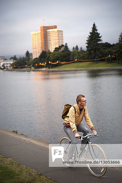 Mann fährt bei Sonnenuntergang Fahrrad am See