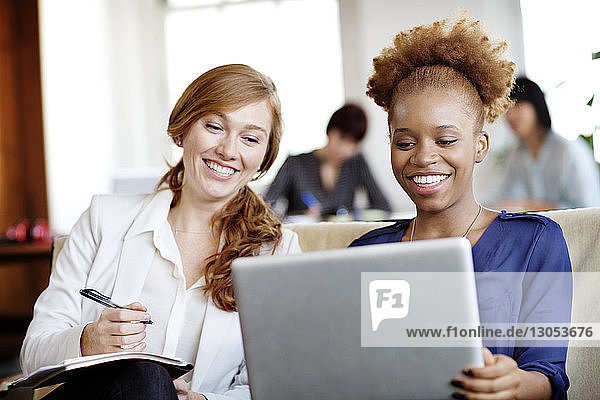 Happy businesswomen using laptop in office