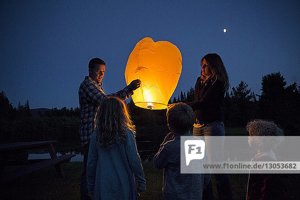 Children looking at parents with illuminated paper lantern