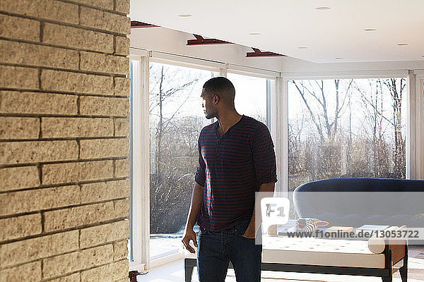 Man looking away while standing in living room at home