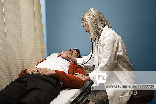 Arzt untersucht Patient mit Stethoskop auf Krankenhausbahre