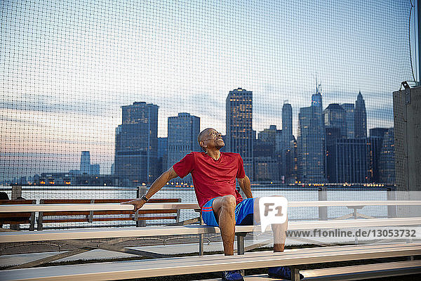 Älterer Mann sitzt bei Sonnenuntergang auf Tribünen gegen die Stadt
