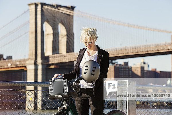 Frau steht mit Fahrrad gegen Brooklyn Bridge in der Stadt